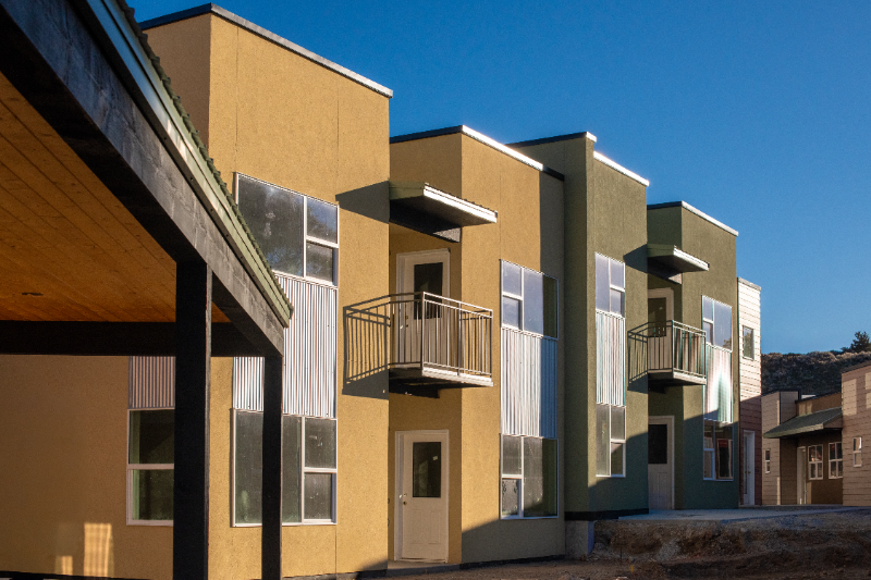 Multi-story residential building with balconies and colorful stucco exterior.
