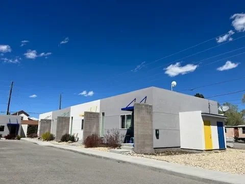 A row of modern, flat-roofed houses with minimalistic design under a bright blue sky.