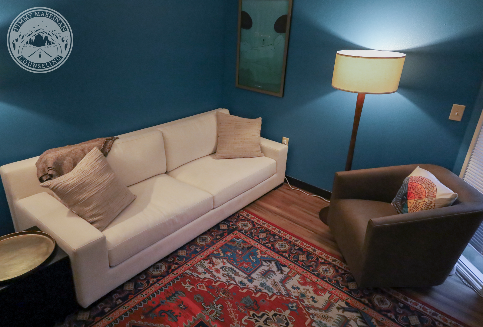 Welcoming Chandler therapy office with comfortable sofa seating, warm lighting, teal walls, and a private counseling space designed for comfort and conversation.