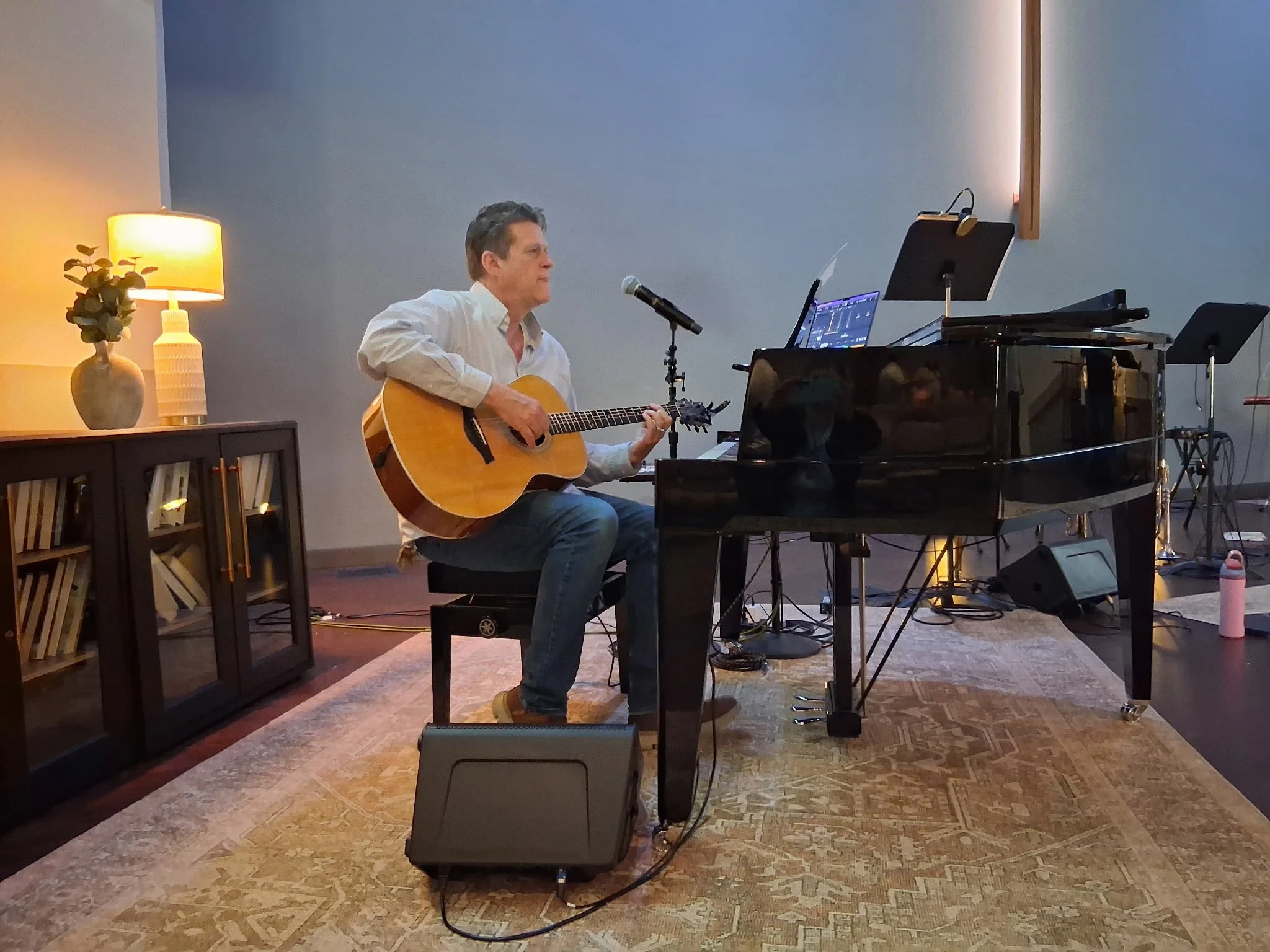 Man sitting at a grand piano and playing guitar