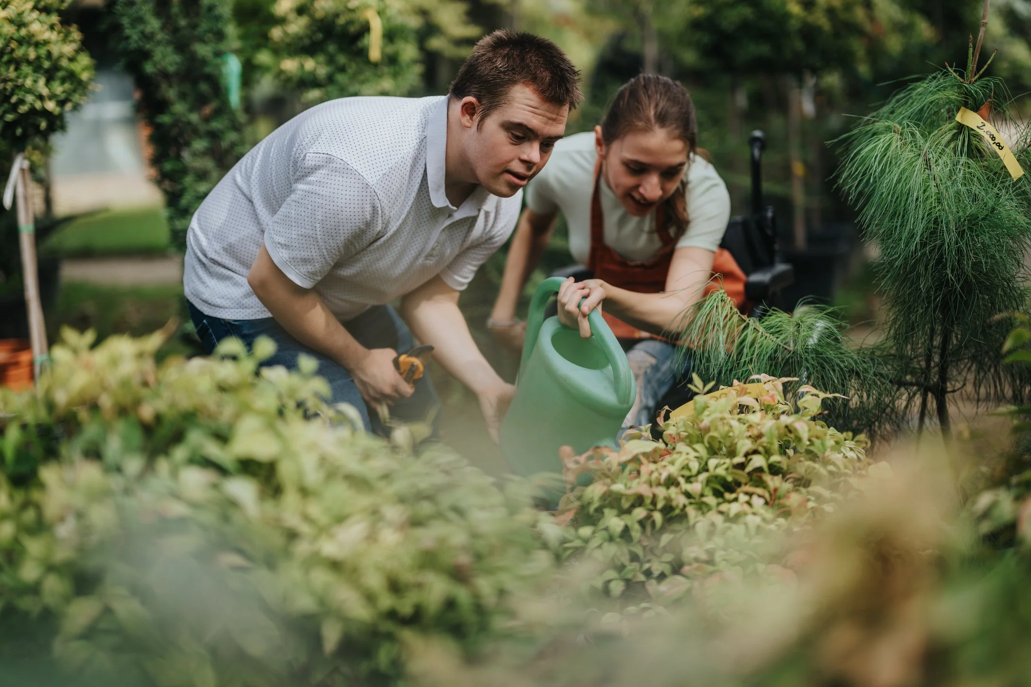 Two young people taking part in a structured gardening activity, watering plants during a Shyft session