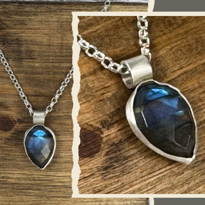Silver necklace with a labradorite teardrop-shaped gemstone pendant on a wooden background.
