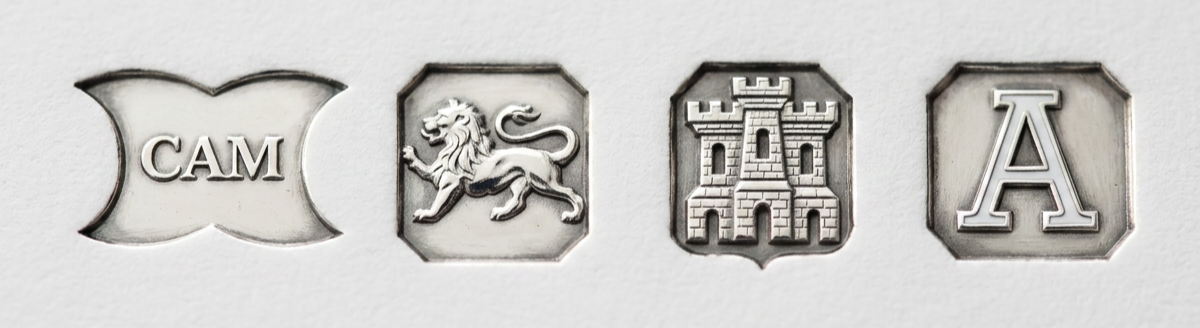 Representative image of UK silver jewellery hallmark - Four metal stamps spelling out CAM (the makers mark), a lion, a castle, and the letter A.