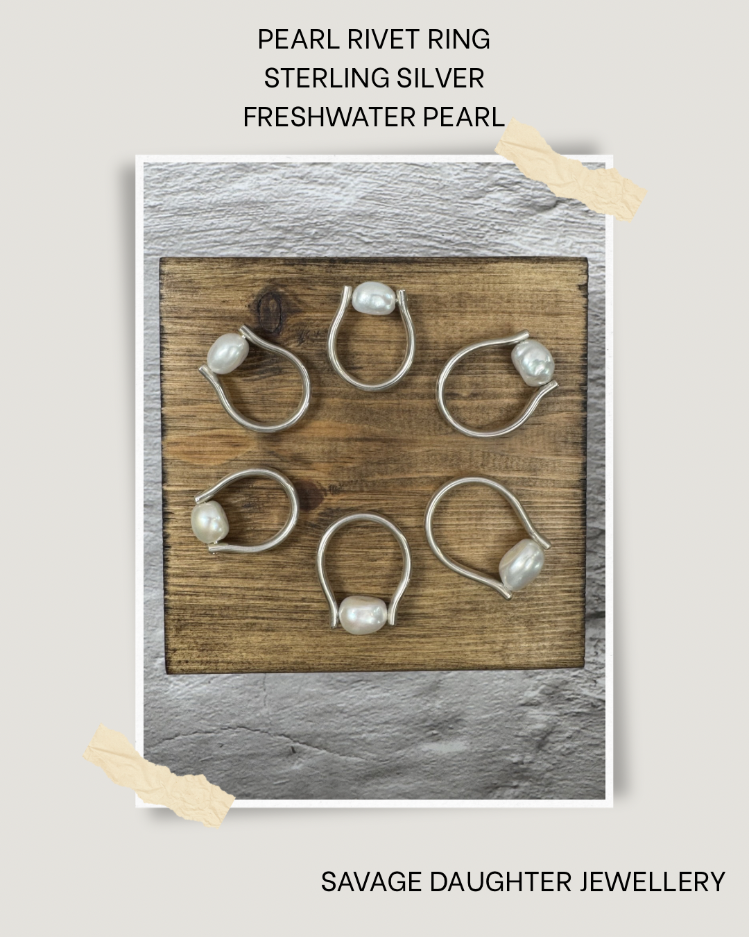 Set of six sterling silver rings with freshwater pearls displayed on a wooden board. The background includes a textured wall with a white paper overlay at the top and bottom, with torn tape-like accents.