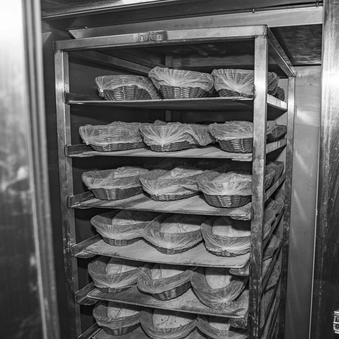 A metal rack filled with baskets covered with cloth in a bakery or bread storage area.