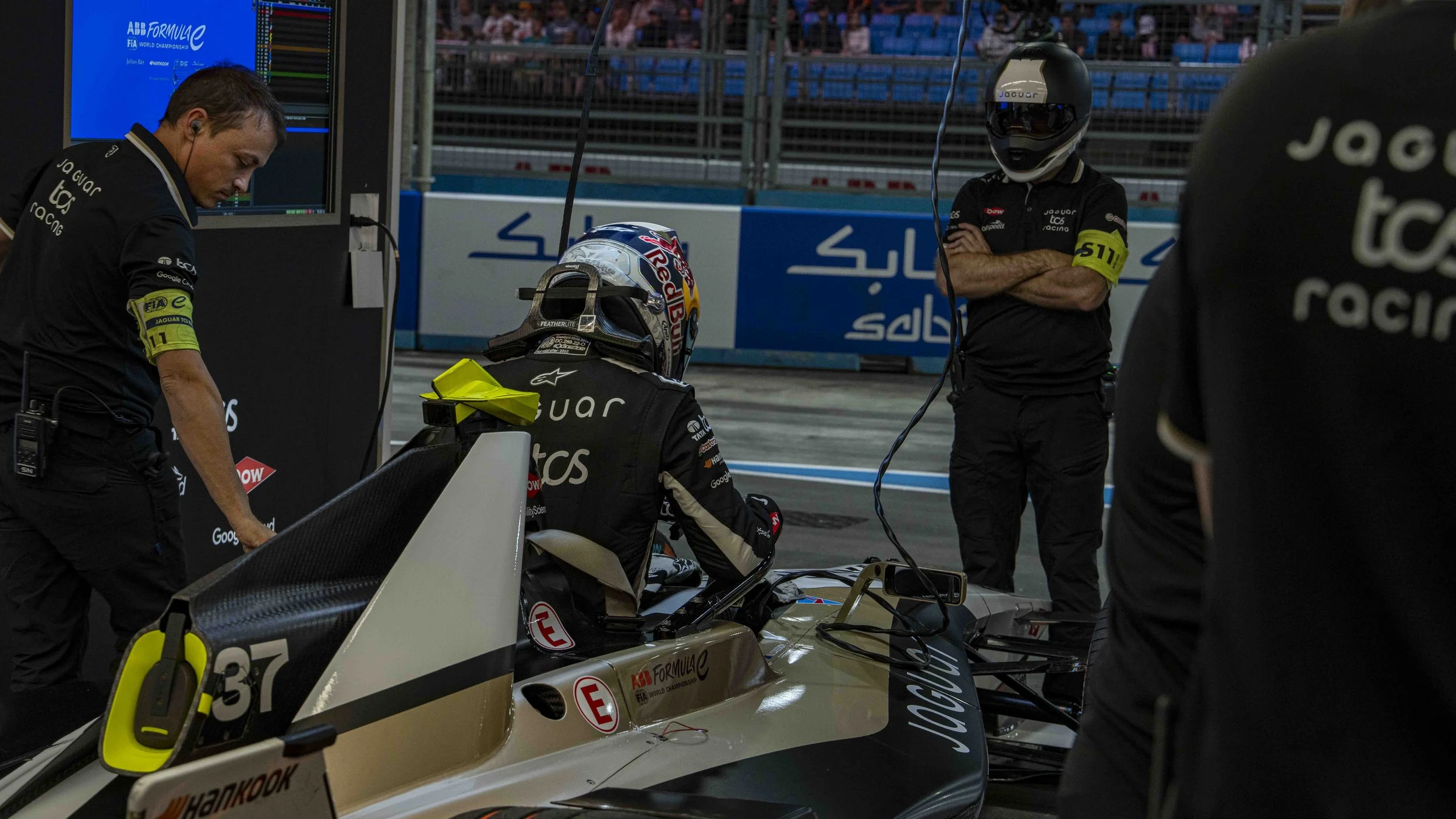 Jaguar TCS Racing Formula E car in the pit with crew members preparing it, including Nick Cassidy, at London Excel.
