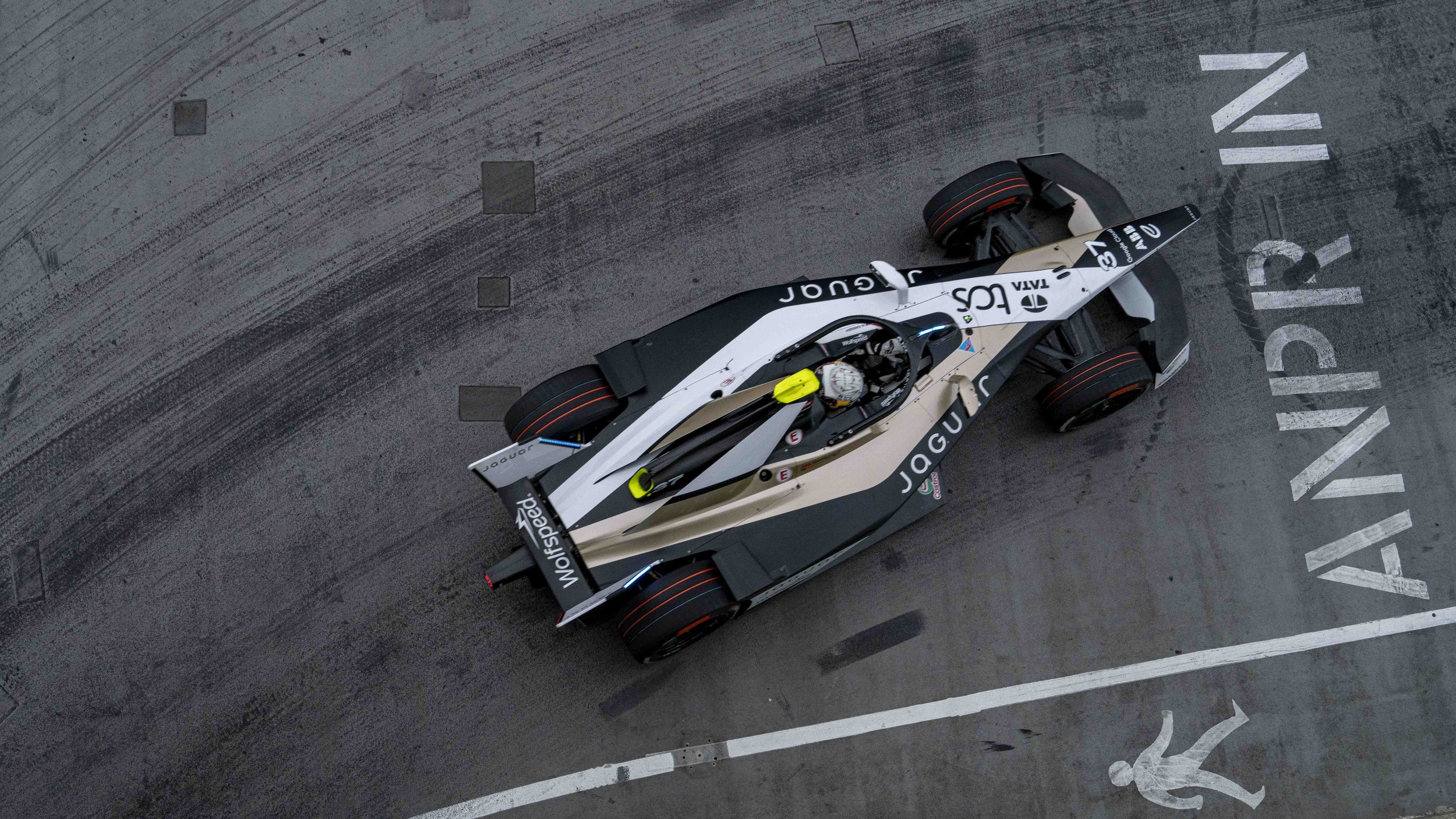 From an aerial view, a sleek Jaguar TCS Racing Formula E race car  is on a race track, 