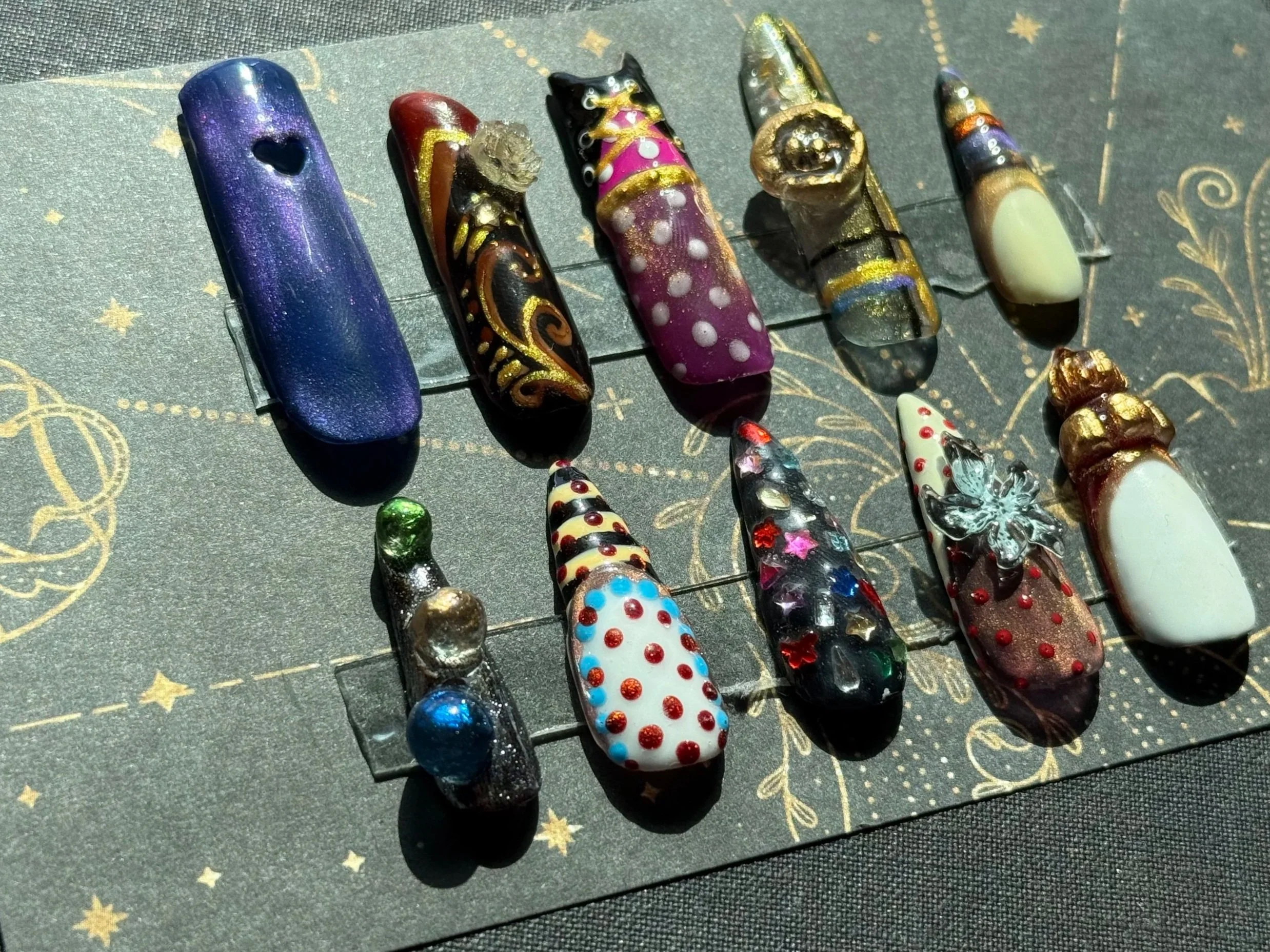 Collection of decorative glass and resin nails with various colors and designs on a dark background.