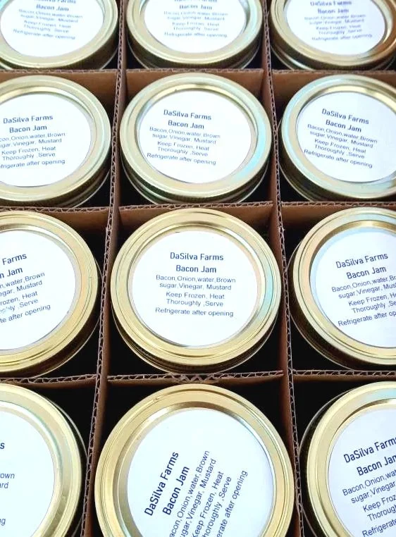 Stacked jars of DaSilva Farms bacon jam in a cardboard box.