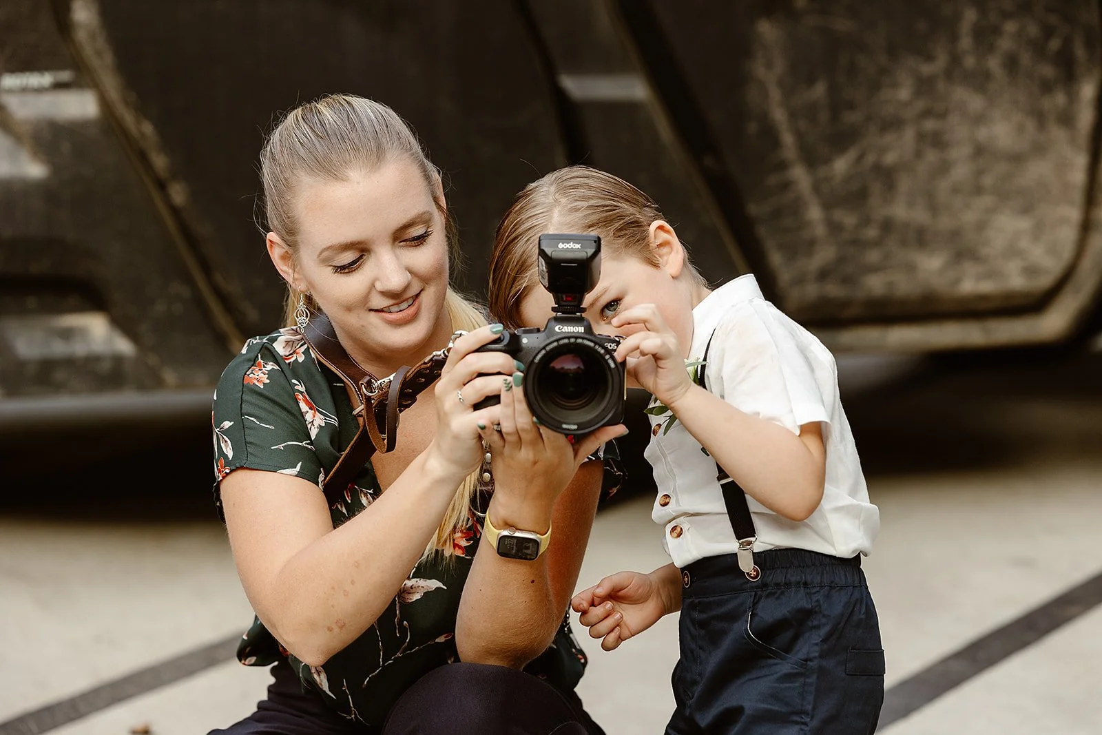 A woman and a young boy looking at a camera together, with the boy peering through the viewfinder.