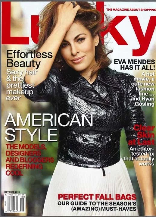 Cover of Lucky magazine featuring Eva Mendes with brown hair, wearing a black leather jacket and white skirt, smiling and posing with her hand on her head. Headlines include 'Effortless Beauty,' 'American Style,' and 'Perfect Fall Bags.'