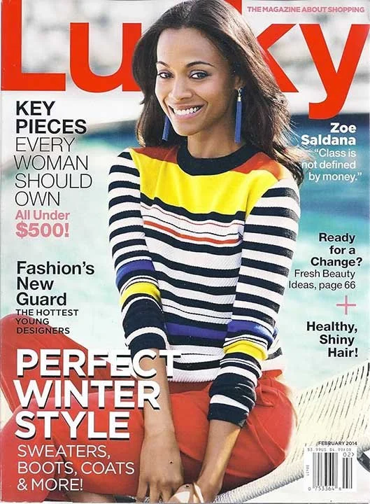 Cover of Lucky magazine featuring a woman with a bright smile, wearing a yellow, black, white, and blue striped sweater, with text highlights about fashion and shopping.