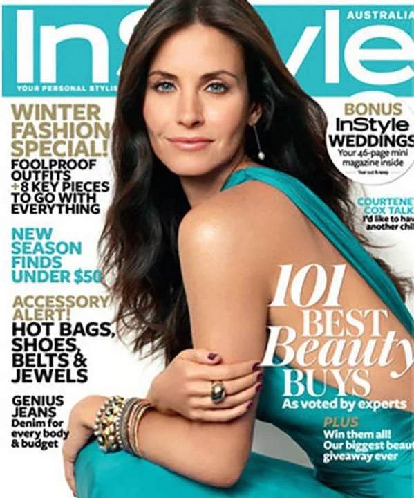 A woman with long dark hair and blue eyes wearing a teal dress, posing on the cover of InStyle magazine.