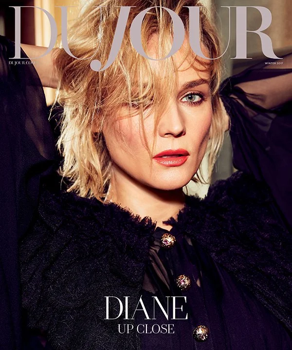 Close-up of a blonde woman with wavy hair, wearing a black outfit with textured details and gold buttons, looking directly at the camera with her hand behind her head, on the cover of D/Your magazine.