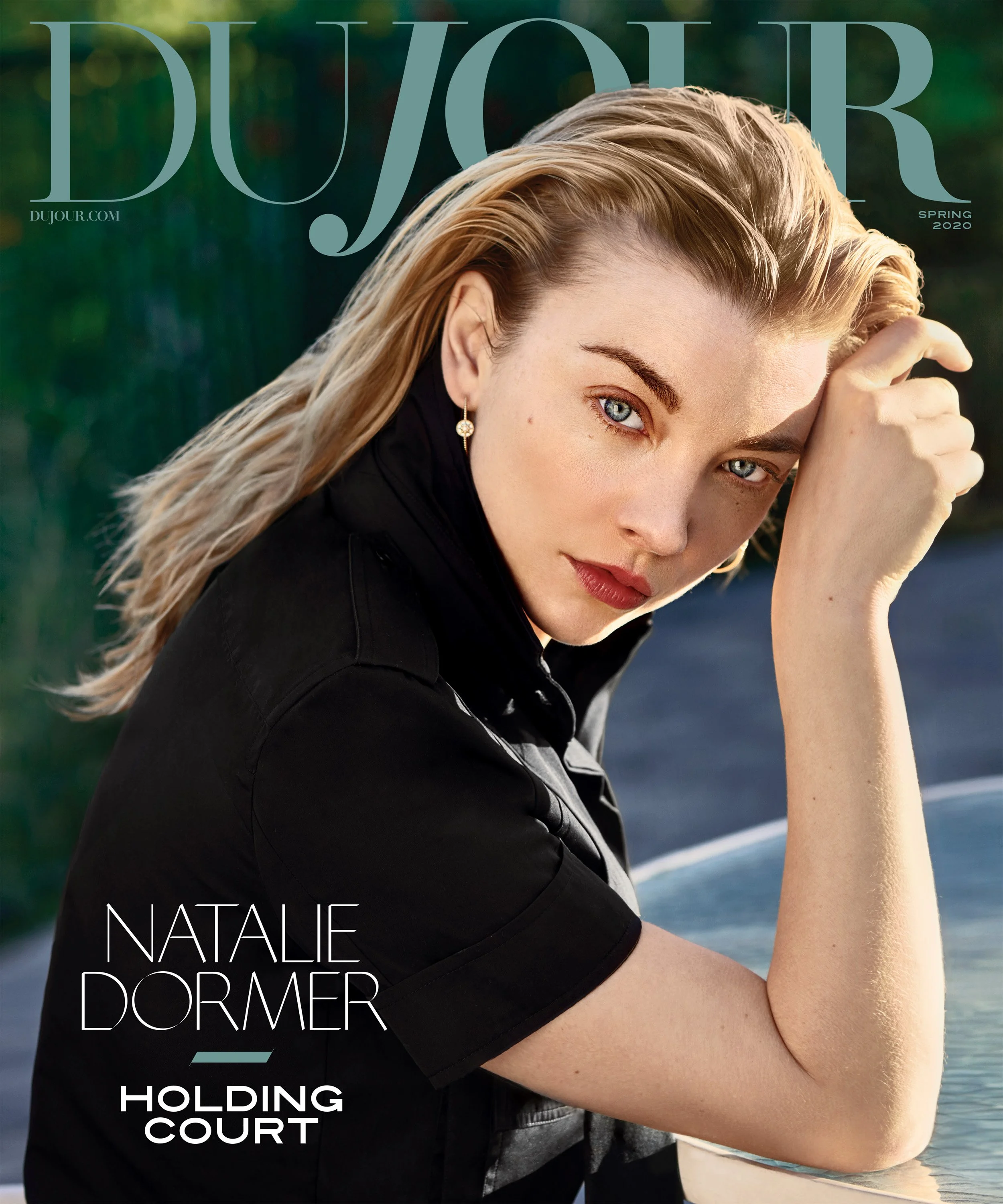 Magazine cover featuring Natalie Dormer with blonde hair, blue eyes, wearing earrings, resting her head on her hand, outdoors with blurred greenery background, titled 'Holding Court'.