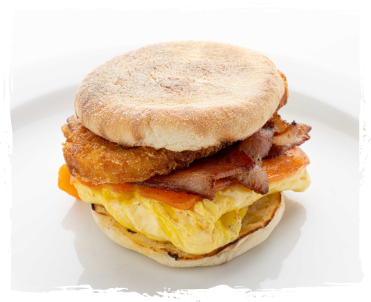 Breakfast sandwich with an English muffin, fried chicken fillet, bacon, scrambled eggs, and melted cheese