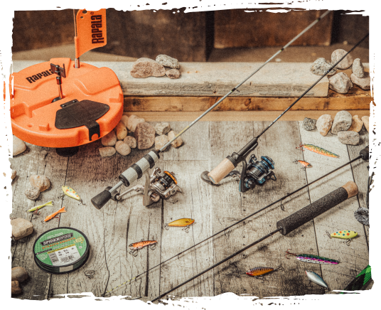 Fishing rods, tackle box, fishing line, small plastic fish lures, rocks, and a wooden surface.