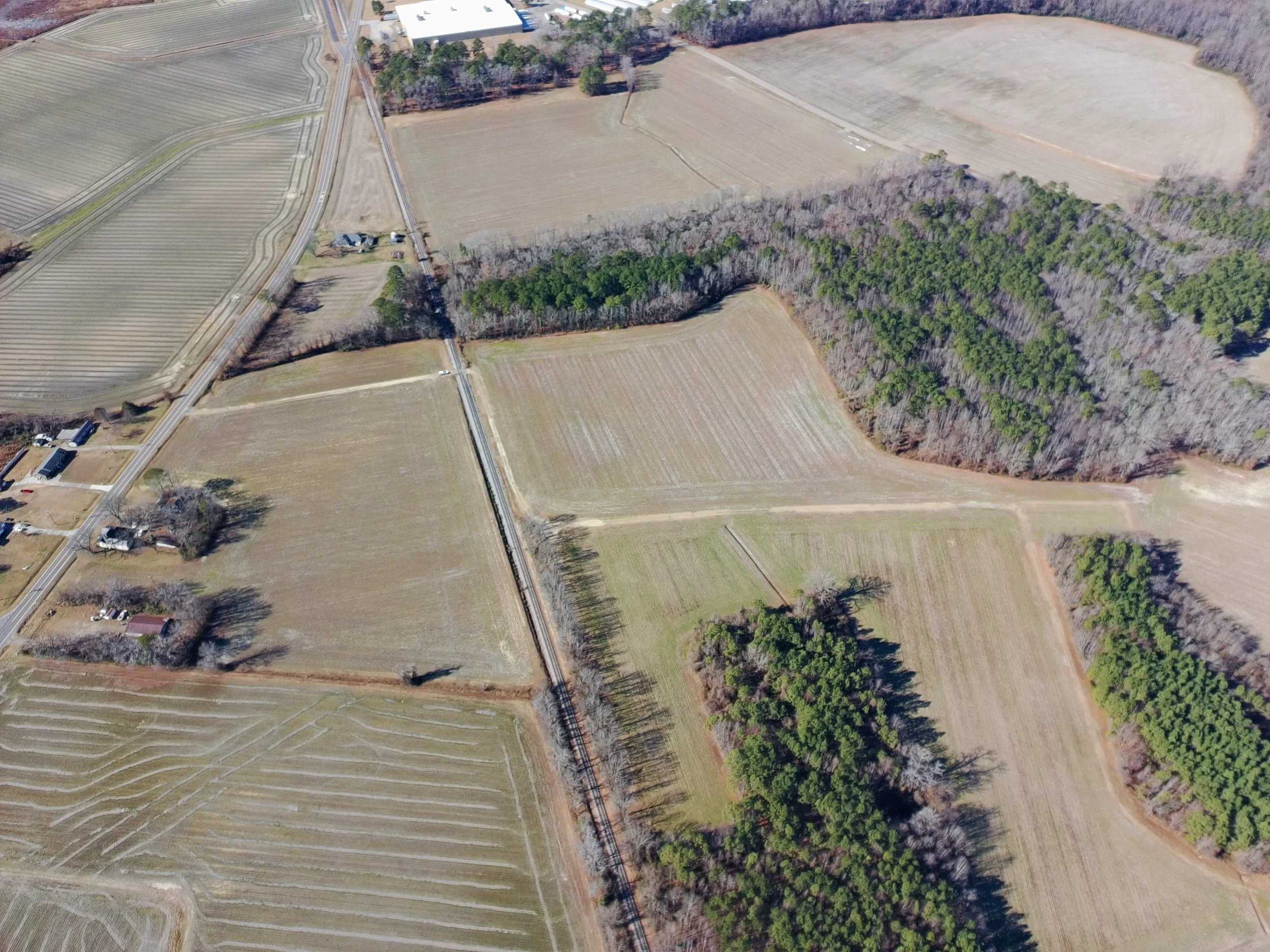 Aerial view of farmland with fields, roads, and patches of trees.