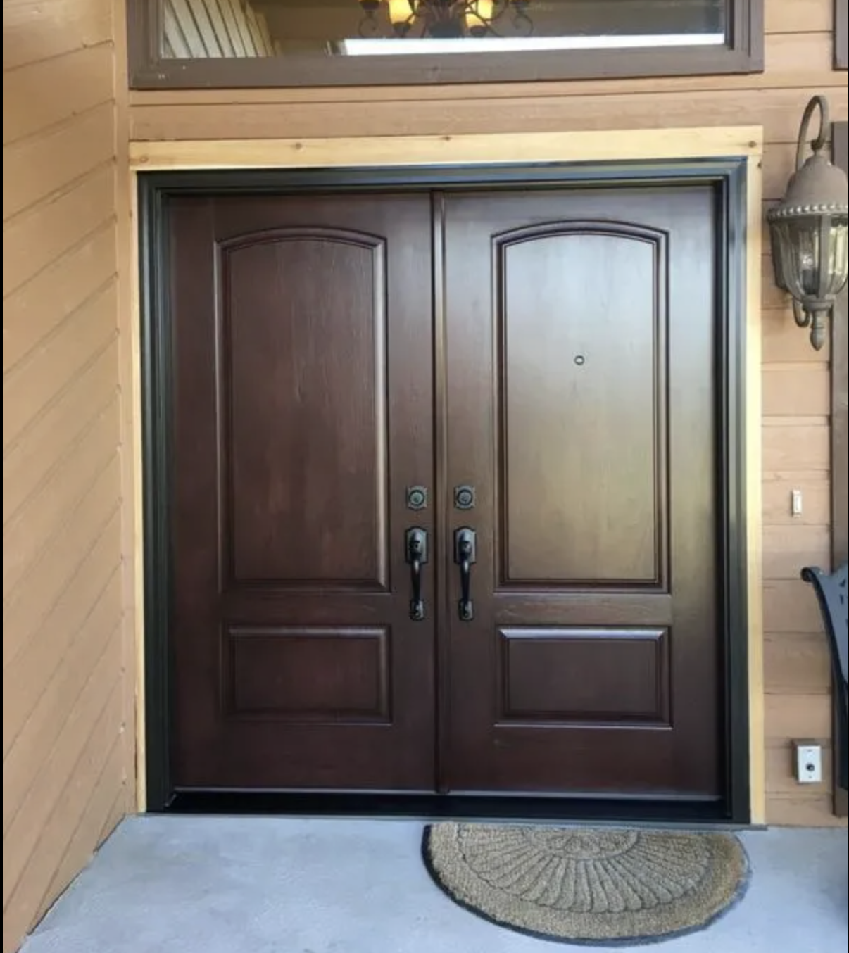 Colorado Springs, Colorado home with a ProVia entry door with black handles, set in a frame on a wooden exterior wall, with a semi-circular doormat in front.