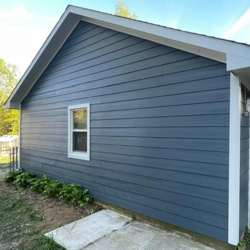 Completed residential home transformation by Oakstone Exteriors featuring premium deep blue James Hardie siding replacement with crisp white exterior trim.