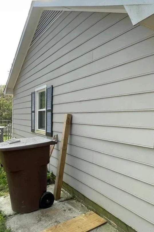 Oakstone Exteriors evaluating old light gray vinyl siding during a residential home exterior repair and inspection.