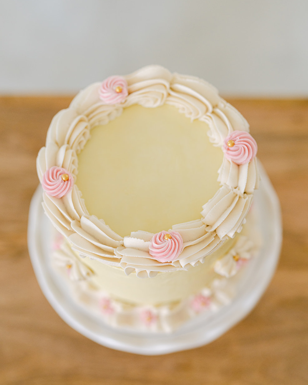 A white frosted cake decorated with piped frosting swirls and embellishments, shown on a white background.
