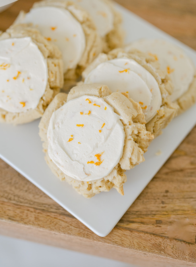 Cookies with white icing and orange zest on a white plate