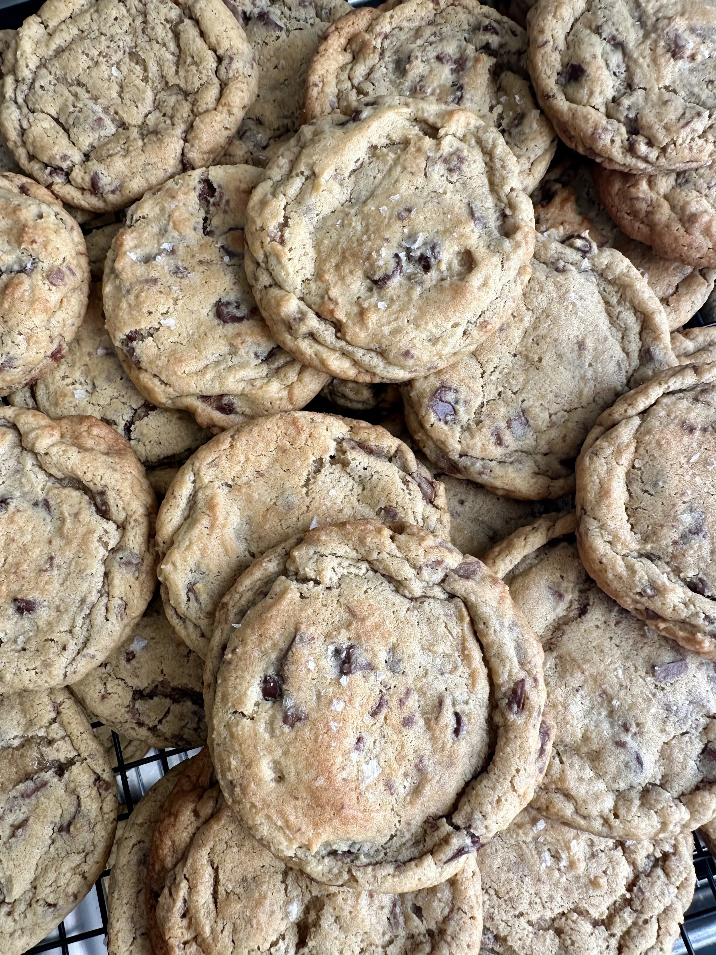 Close-up of assorted chocolate chip cookies on a wire rack.