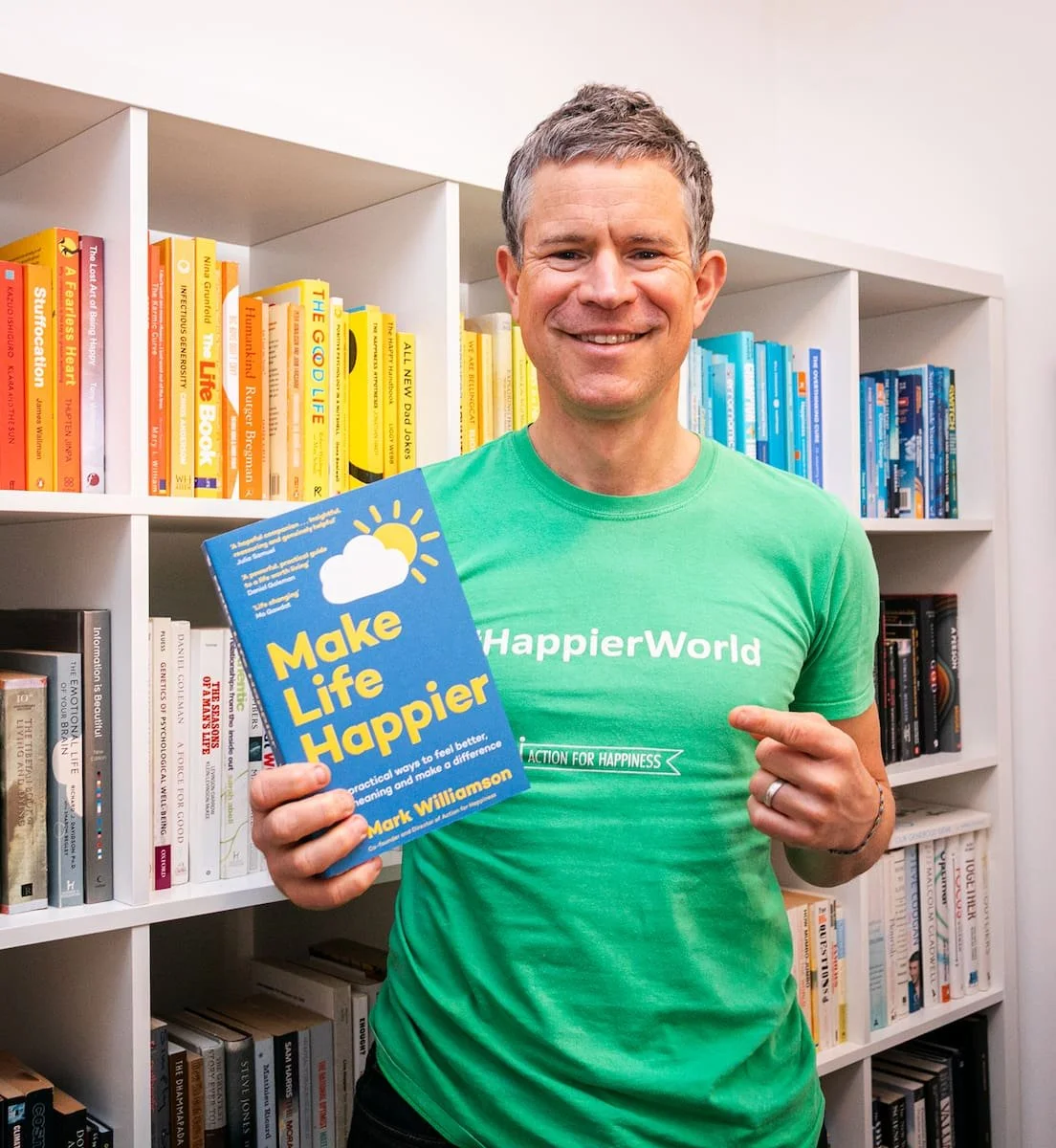 Dr Mark Williamson holding his Make Life Happier book