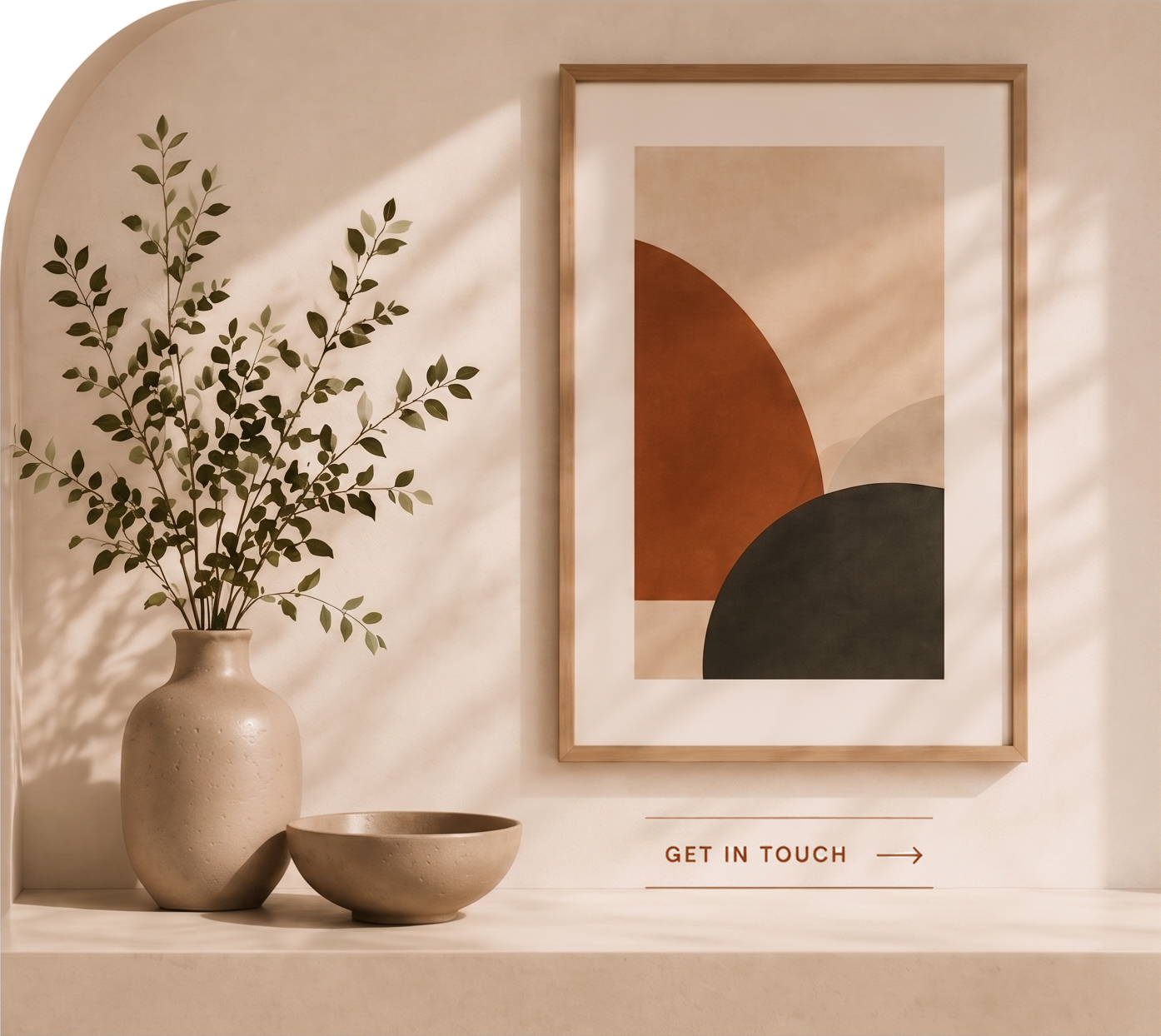 Decorative interior with a beige vase holding green leafy branches, a matching bowl, a framed abstract art print with earthy tones, and a sign that says 'Get in Touch' with an arrow.