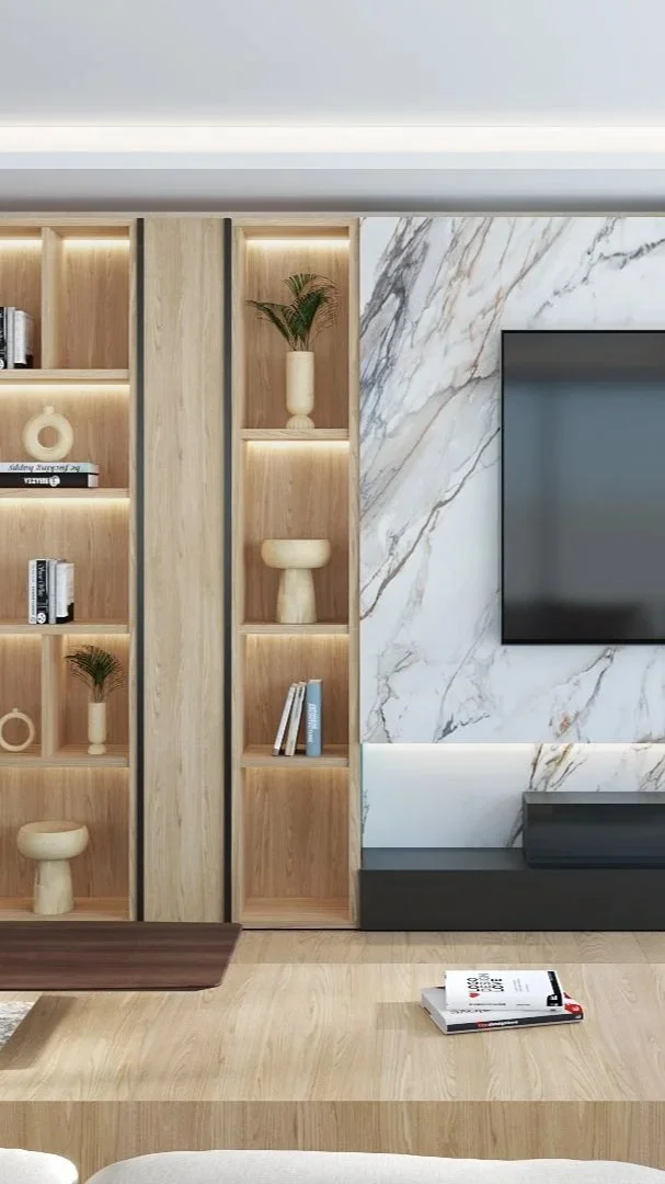 Estantería de madera con libros y decoraciones, pared de mármol con pantalla de televisión, y piso de madera en una sala moderna.