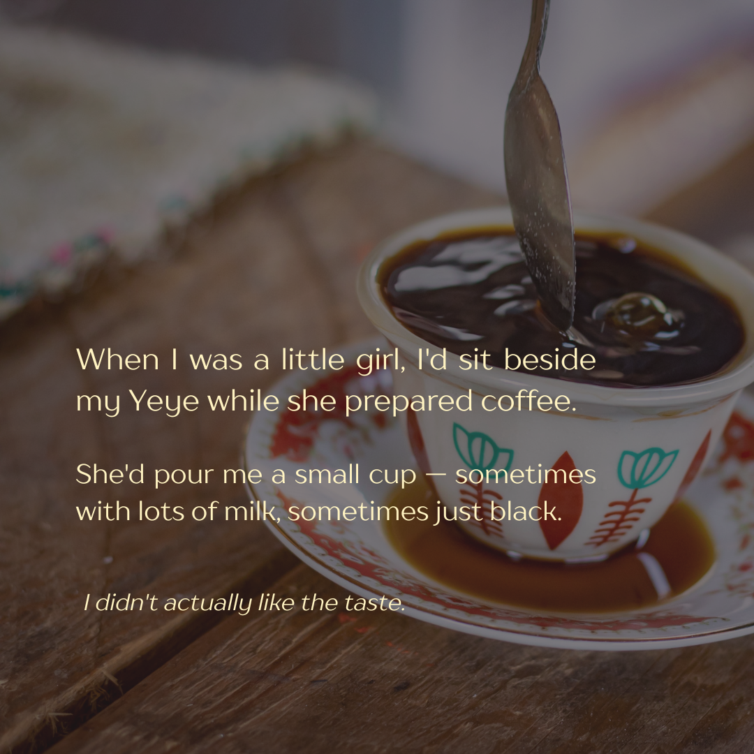 A cup filled with black coffee on a saucer, with a spoon stirring the coffee. The cup has a colorful floral design.