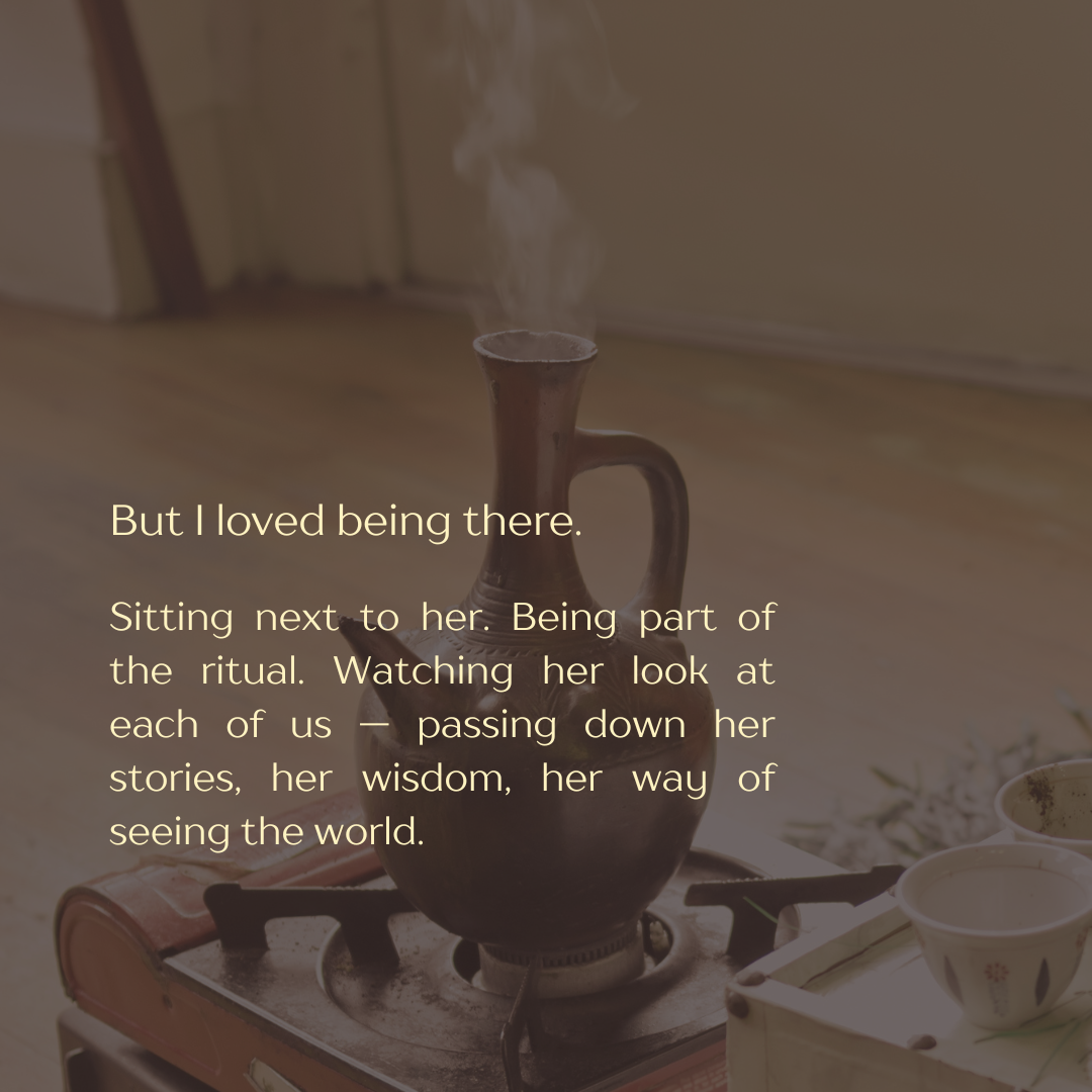 A steaming brown ceramic coffee pot on a stove with two small bowls and a wooden container nearby.
