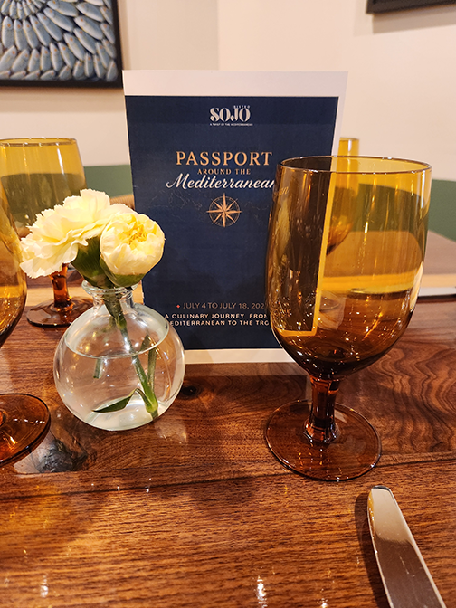 Passport pamphlete sit on a table with flowers and a glass.