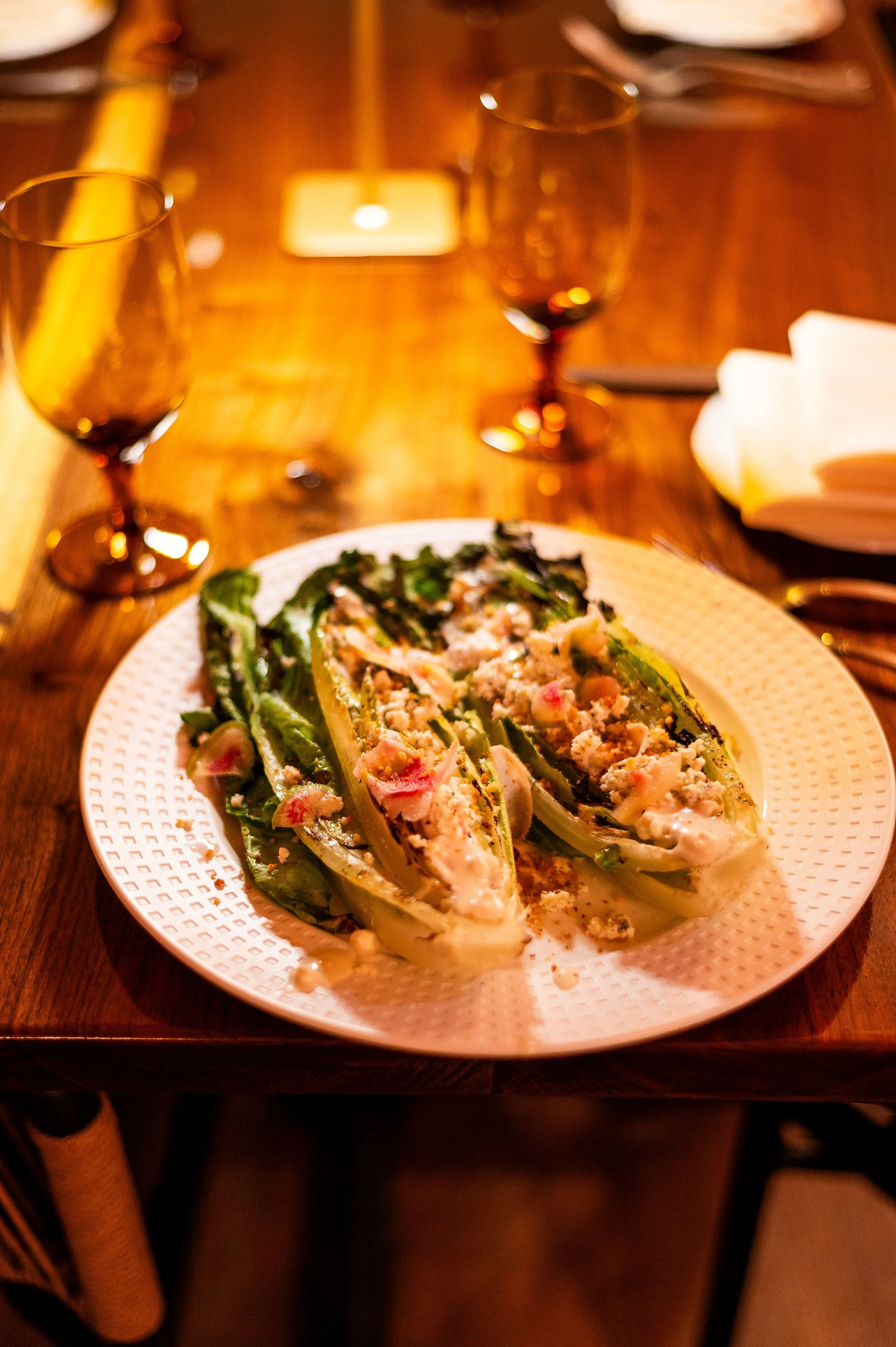 Grilled romaine hearts salad topped with crumbled cheese and radishes, a signature Mediterranean starter.