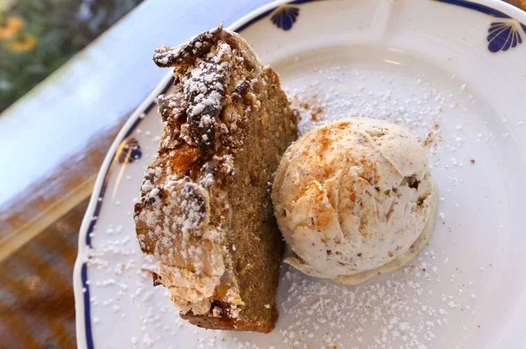 Slice of apple crisp with a scoop of vanilla ice cream on a white plate with a blue floral pattern.