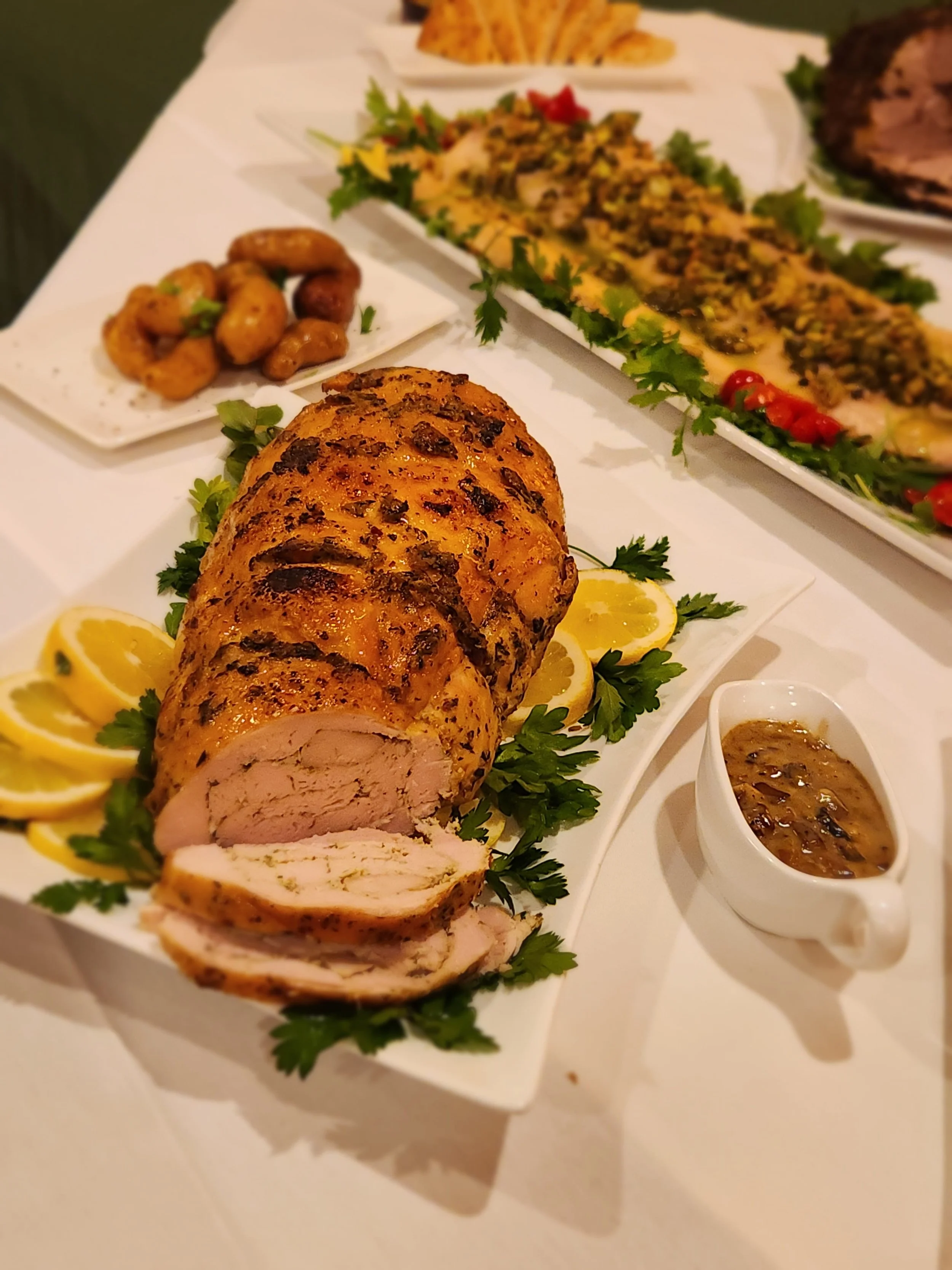 Turkey Roulade on a table with gravy and salmon