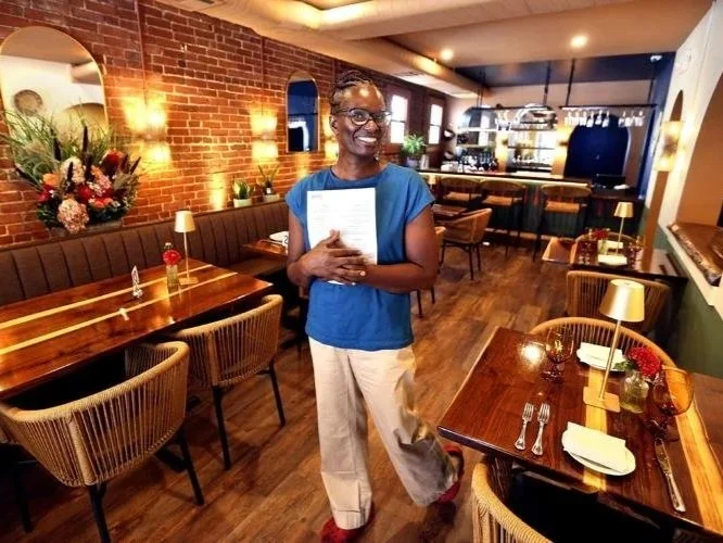 Co-owner, Martha Addison, looks at the camera and holds the Bistro SOJO menu.