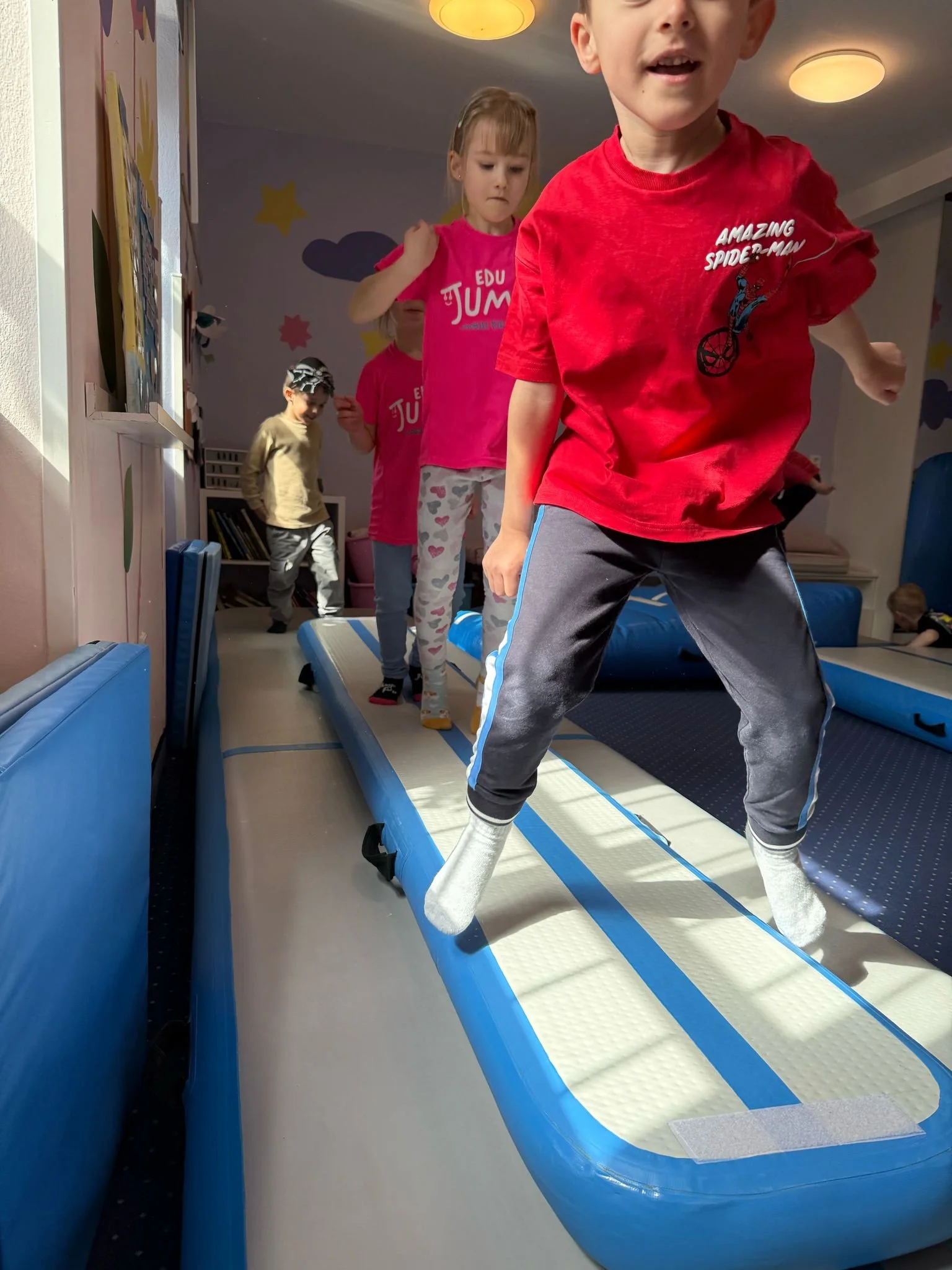 Children playing on an inflatable balance beam in a playroom.