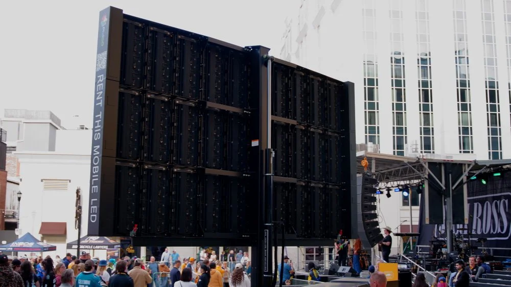 Large outdoor LED screen with the text 'RENT THIS MOBILE LED' at a public event.