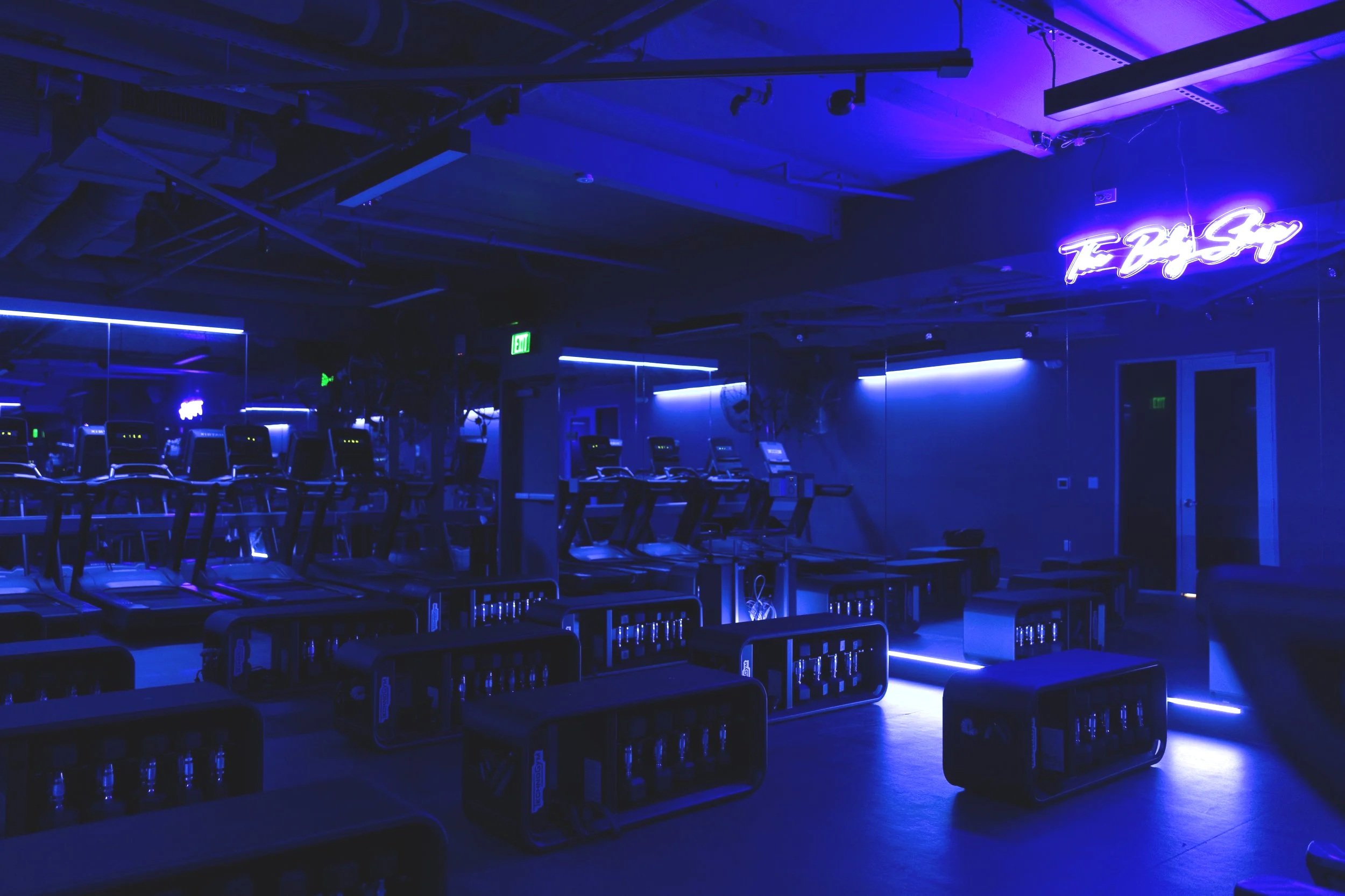 Interior of a energetic fitness studio with treadmill machines illuminated by neon lighting,