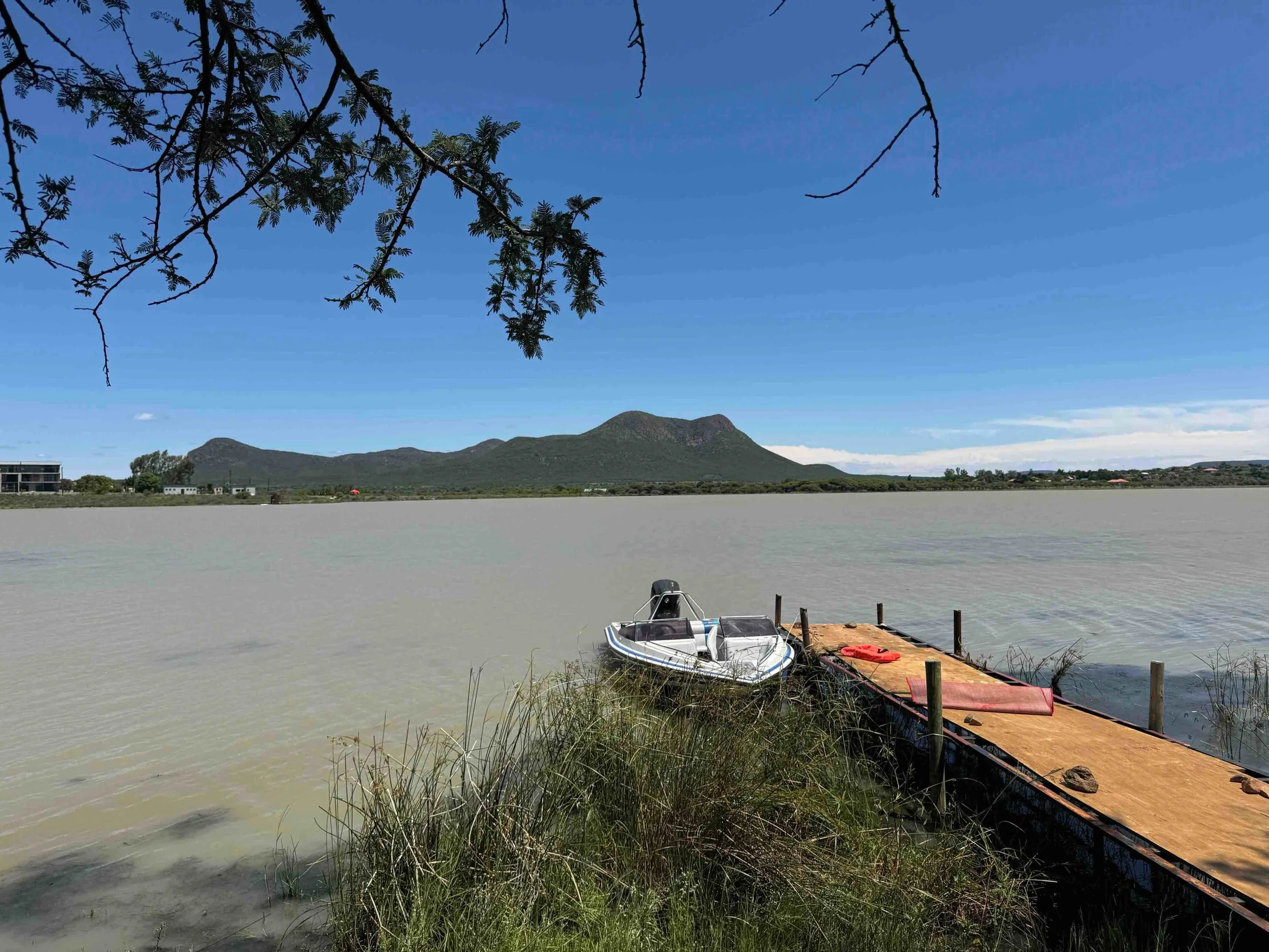 Mogobane Dam in Botswana with deck and motorboat and view onto Otse Hill