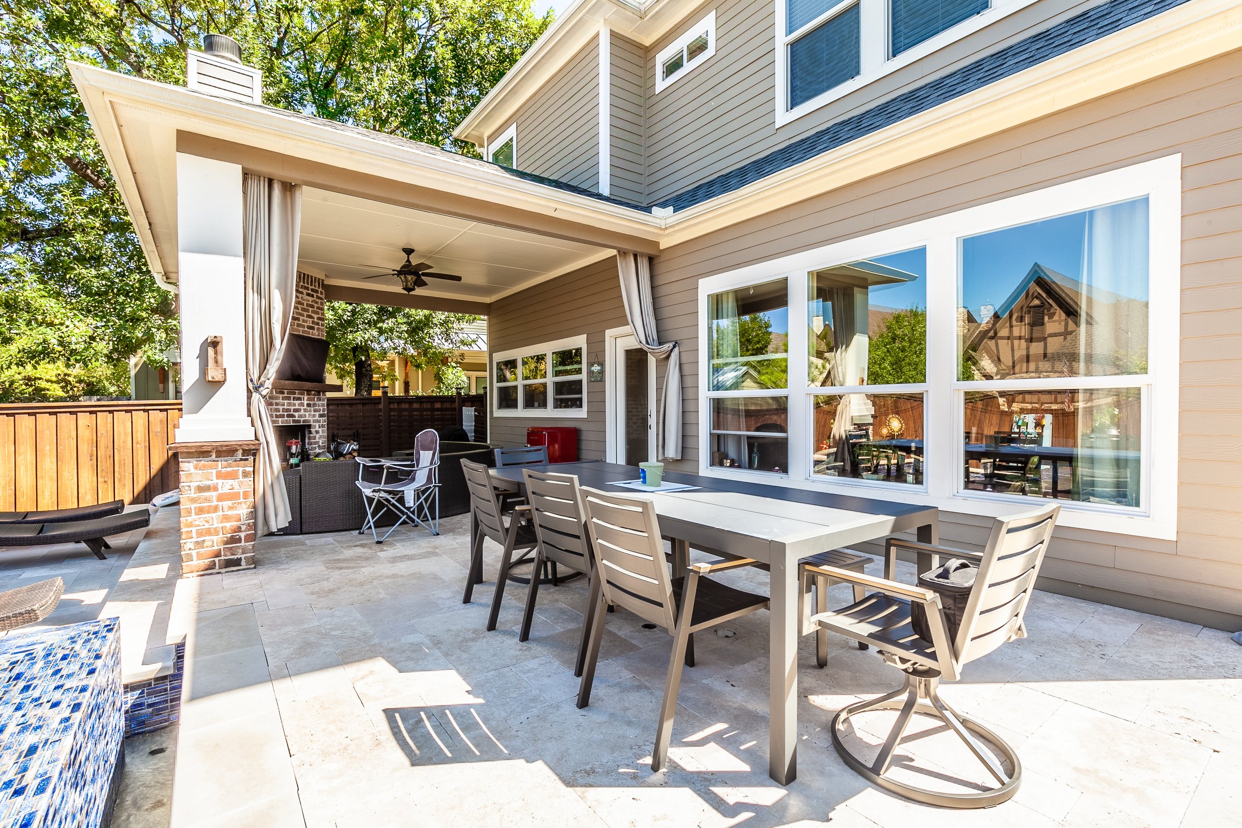 Backyard patio with outdoor dining table, chairs, and a covered seating area with a chimney