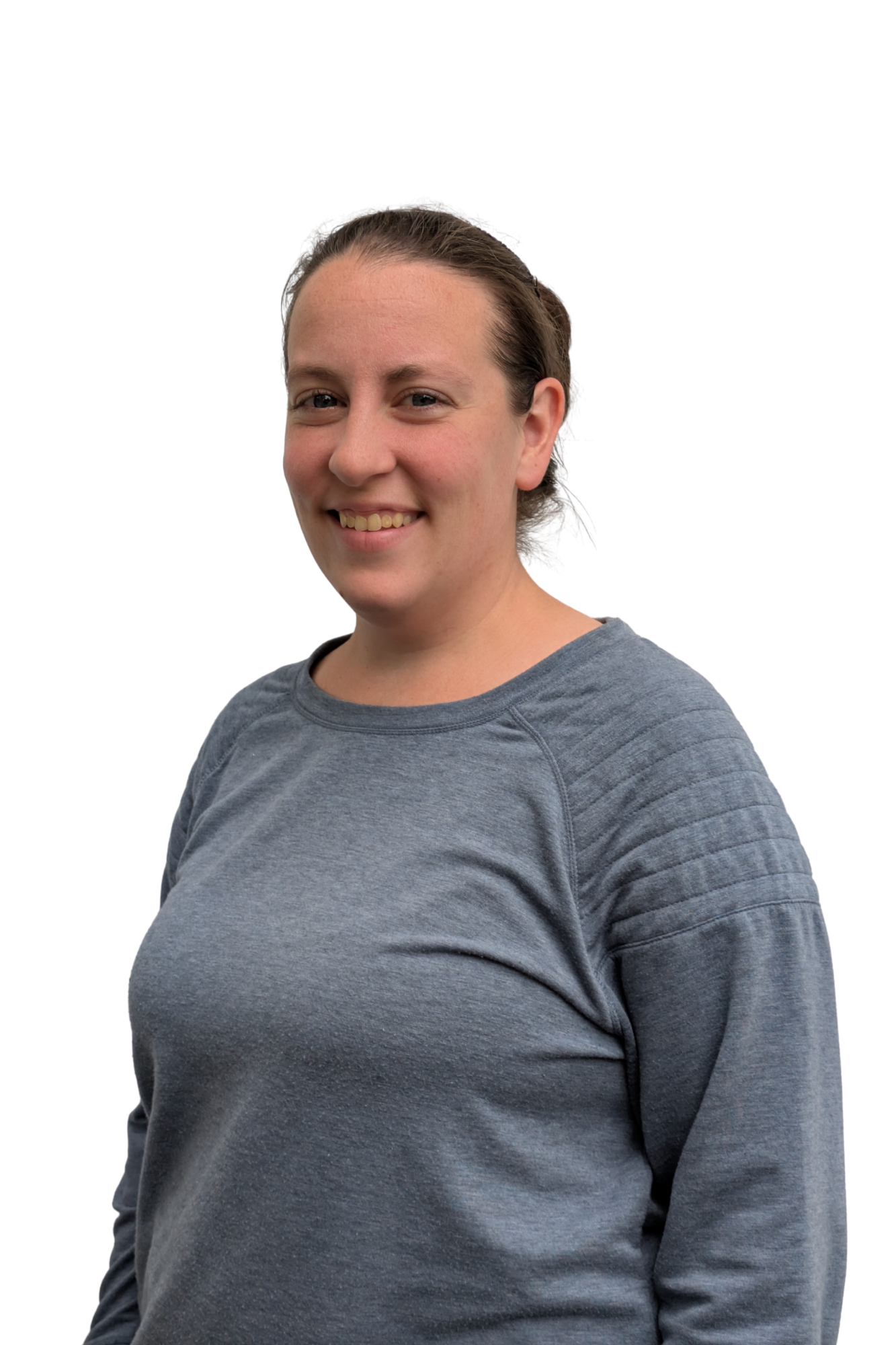 A woman with brown hair tied back, wearing a gray long-sleeve shirt, smiling and looking at the camera, against a plain white background.