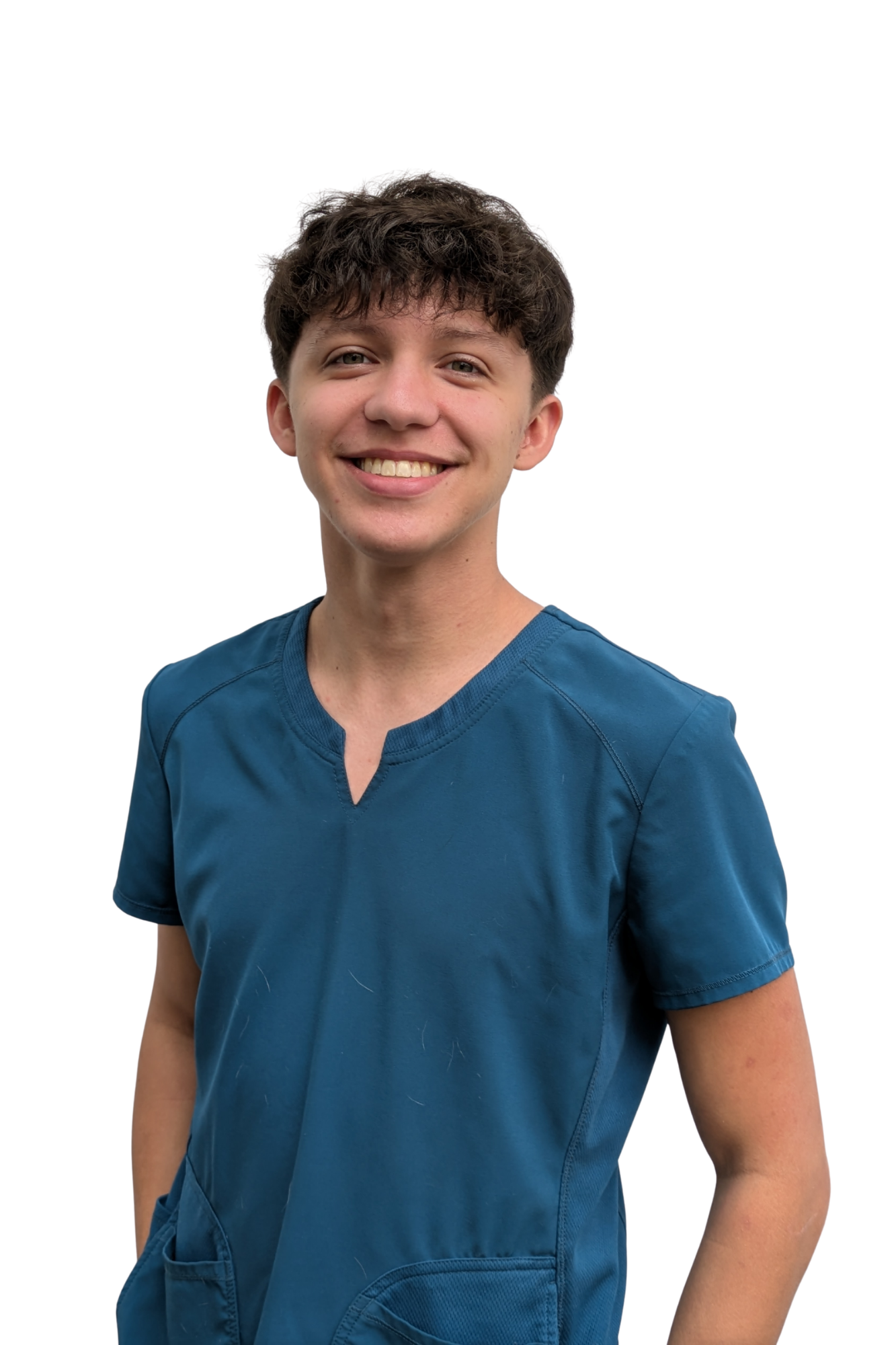 A young man with short, curly brown hair smiling, wearing a blue medical scrub top with a V-neck and short sleeves, standing against a plain white background.