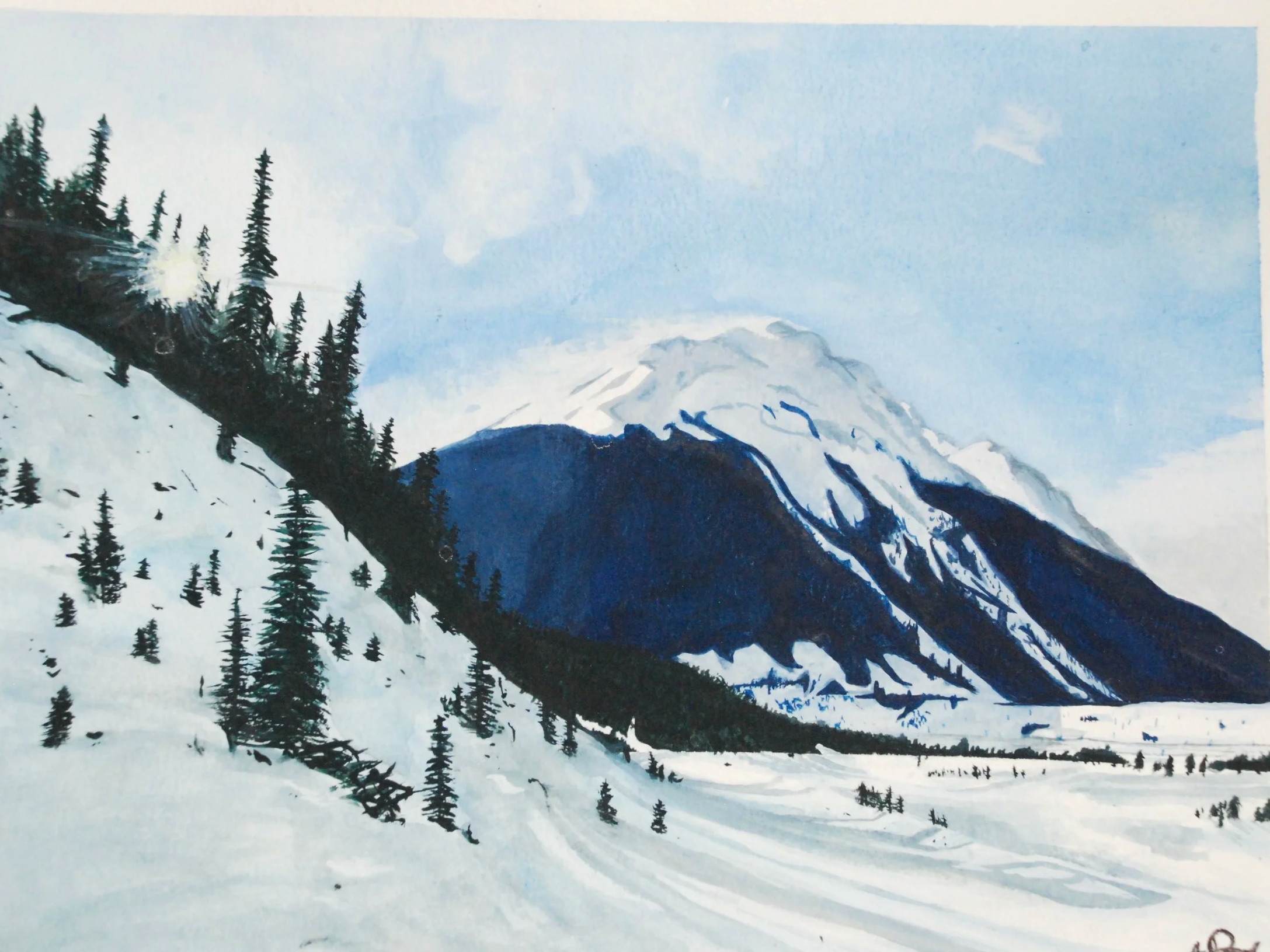 A snow-covered mountain landscape with a large mountain in the background, evergreen trees on a hillside to the left, and a snowfield in the foreground under a partly cloudy sky.
