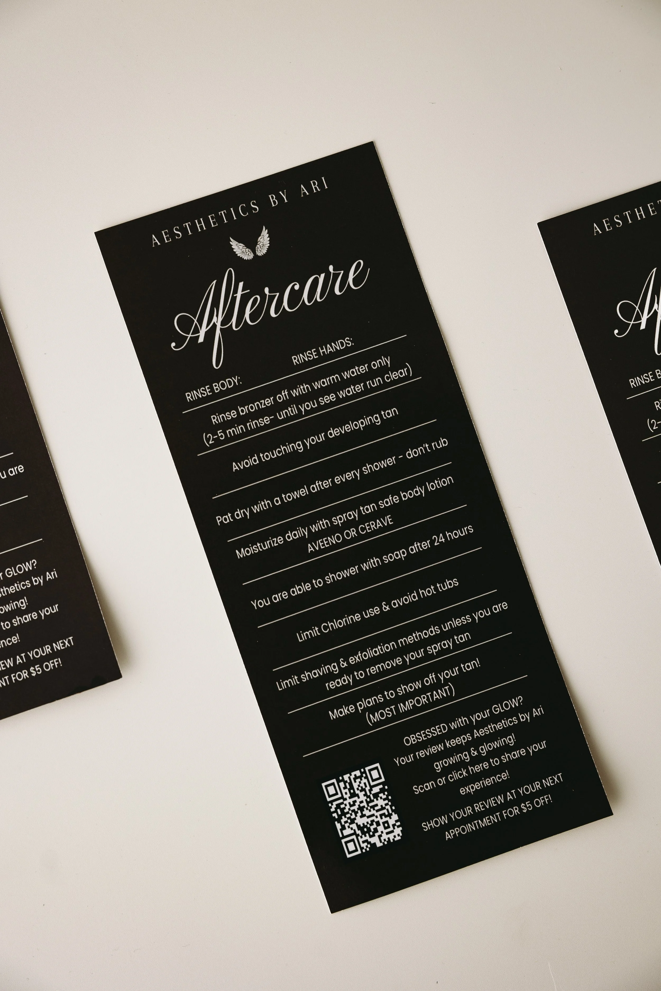 Black flyer with white text titled 'Aftercare' from Aesthetics by Ari. Instructions for post-treatment skincare, including rinsing, avoiding touching the skin, and avoiding hot tubs. Contains a QR code at the bottom.