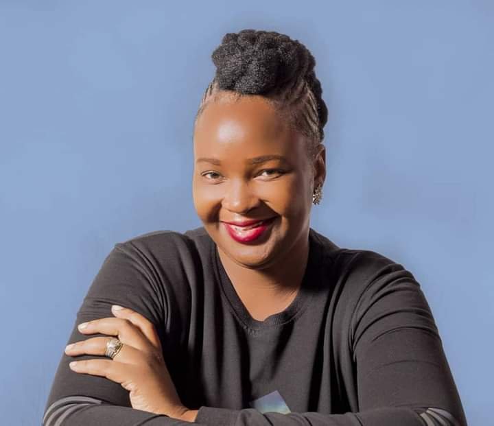 A woman smiles toward the camera with her arms crossed.