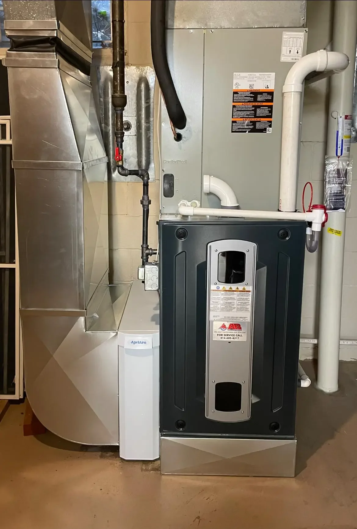 A furnace water heater system in a utility room with pipes, a filter, and a silver metal HVAC unit.