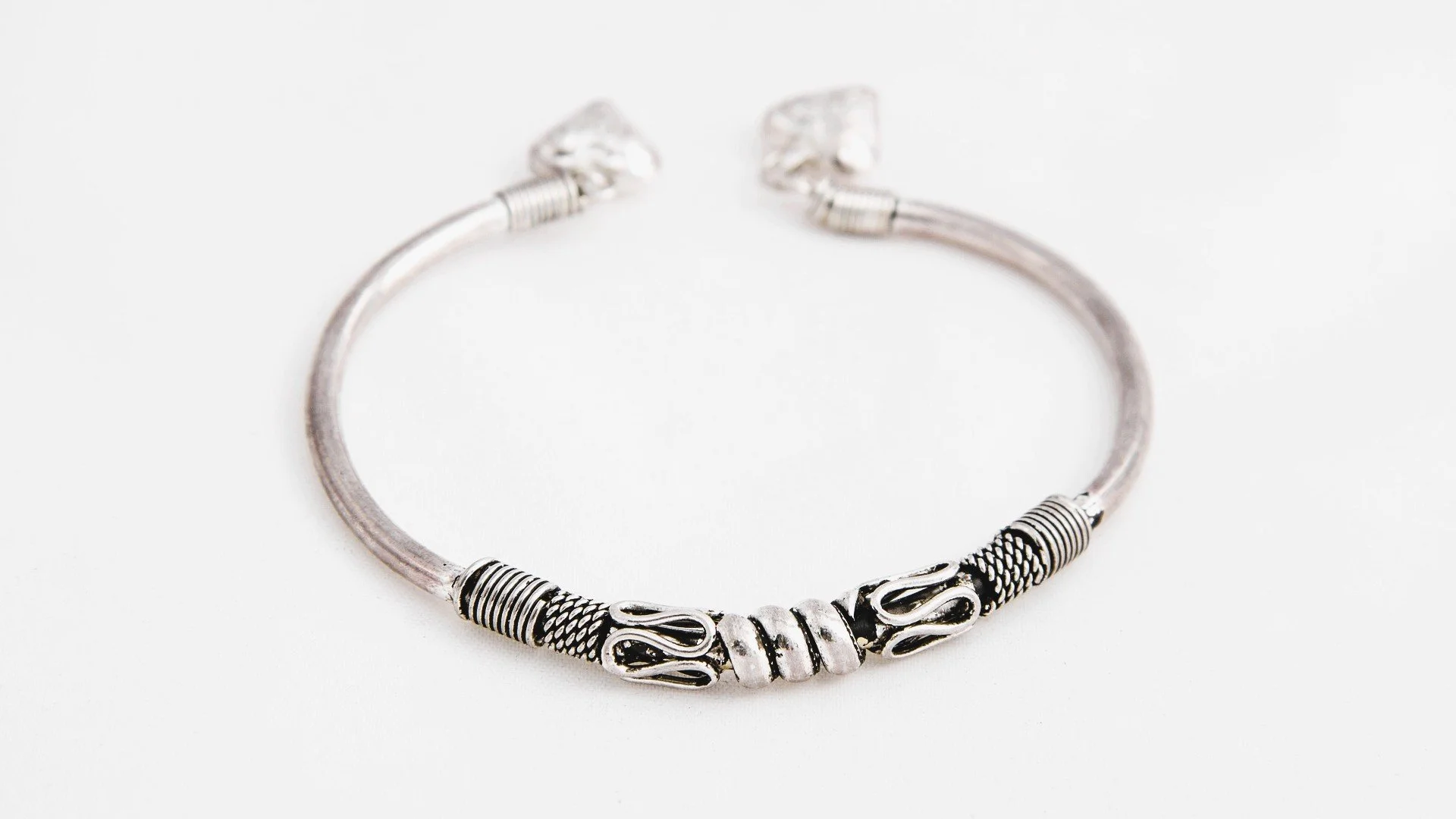 Silver necklace with intricate design, placed on a white background.